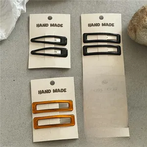 Detail of resin rectangle and waterdrop hair clips in amber and black on card