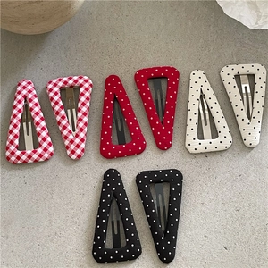 Détail de barrettes en tissu géométriques avec pois et carreaux rouges et noirs