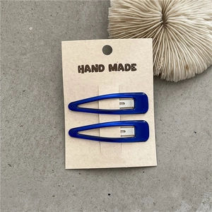 Detail of two dark blue translucent resin snap clips on handmade kraft paper card