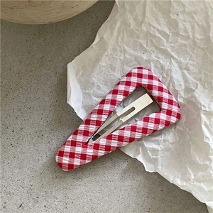 Gros plan sur la barrette triangle à carreaux rouges et blancs sur fond texturé blanc