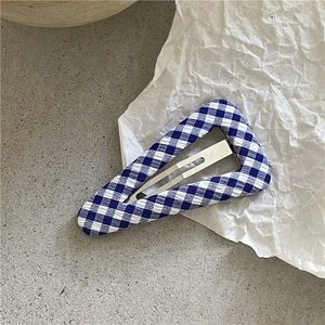 Gros plan détaillé d'une pince à cheveux triangulaire à carreaux bleus et blancs vichy