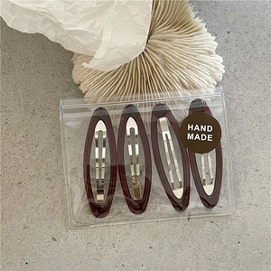 Detailed view of four handmade dark resin oval hair clips in a professional package