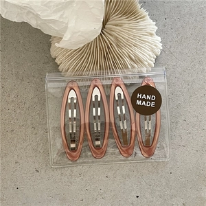 Detailed view of four colorful marble resin hair clips in handmade PVC zipper packaging