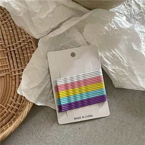Macro view of colorful matte metal hair clips neatly arranged on a white display card