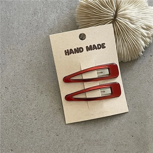 Detail of red teardrop resin hair clips on handmade card with aesthetic coral decor