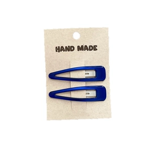 Set of two navy blue oil-dripping snap hair clips on a kraft paper handmade card