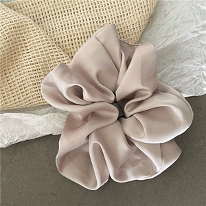 Detail eines großen champagnerfarbenen Satin-Scrunchies mit weicher Textur