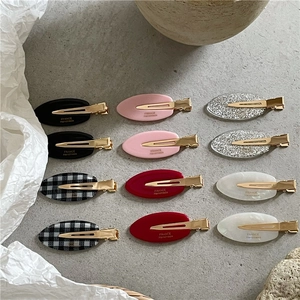 Vue détaillée de barrettes ovales vintage avec motifs à carreaux et finitions pailletées