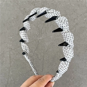 Detail shot of a black and white polka dot headband featuring non-slip inner teeth