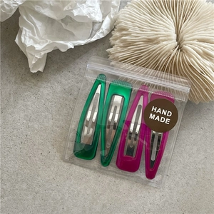 Detailed set of four colorful resin hair clips in vibrant green and magenta with gift bag
