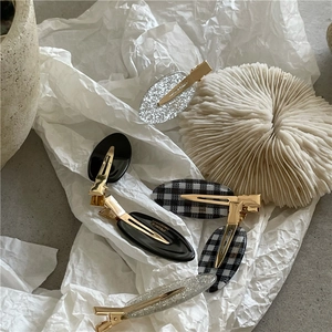 Détail de barrettes ovales pailletées et à damier avec clip en métal doré fait main