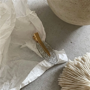 Détail de la pince à cheveux ovale avec paillettes argentées et base en métal doré