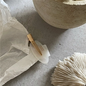 Détail d'une pince à cheveux dorée élégante avec texture marbre blanc et inscription fait main