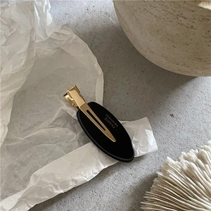Détail de la pince à cheveux ovale noire avec texte France Handmade sur clip doré