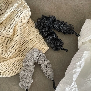 Dettaglio di fermagli a banana in tulle a pois con tessuto plissettato su superficie grigia