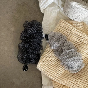 Dettaglio di fermagli a banana in rete a pois con design plissettato ed eleganti balze