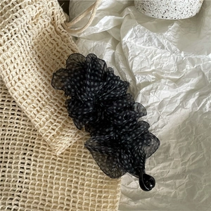 Dettaglio scrunchie in rete a pois bianchi su eleganti trame di tessuto a pieghe