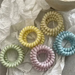 Lot de cinq élastiques à cheveux spirales aux couleurs macaron sur fond minimaliste