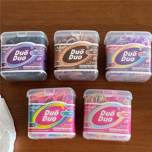 Detail of colorful TPU elastic hair ties in transparent storage boxes on a wooden surface