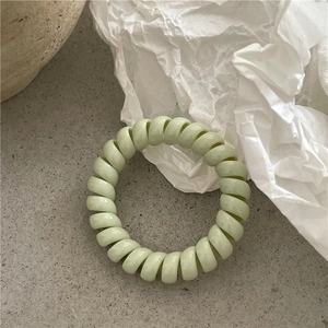 Gros plan sur l'élastique à cheveux spirale vert pastel à haute élasticité