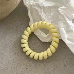 Détail d'un chouchou spirale jaune clair sur une surface minimaliste texturée