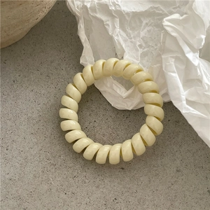 Détail d'un chouchou spirale crème sur un fond texturé minimaliste avec lumière douce
