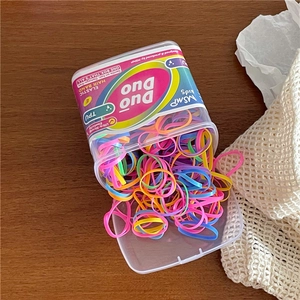 Close-up of colorful elastic hair bands in a box with vibrant candy colors on wood