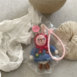 Detail of handmade wool felt bunny charm in clear packaging with pink heart chain