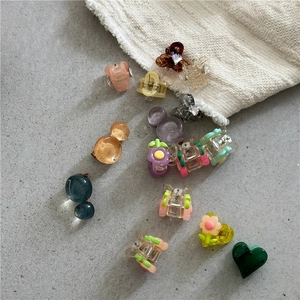 Close-up of colorful resin flower and heart mini hair claws on a textured surface
