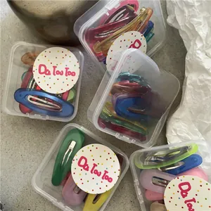 Dettaglio di fermagli per capelli in metallo colorato in scatole di plastica trasparente