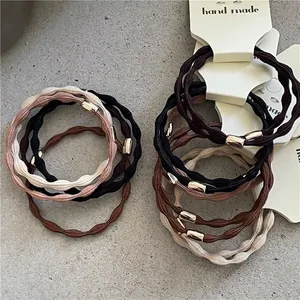 Neutral tones elastic hair ties set with wave texture and gold metal accents on stone background