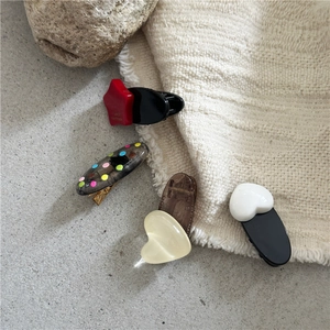 Detail of colorful resin hair clips with star, heart and oval shapes on textured fabric