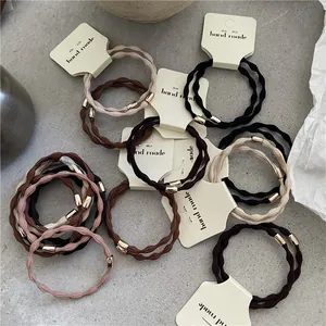 Detail of assorted elastic hair ties in neutral colors with golden metallic beads