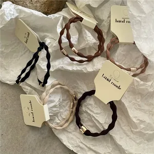 Set of minimalist wavy elastic hair ties in neutral tones with golden metal tube clasp