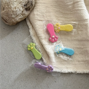 Close-up of pastel cat claw hair clips with 3D heart pads on textured fabric