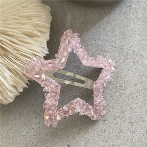 Dettaglio del fermaglio per capelli a stella con cristalli rosa su base di pietra grigia