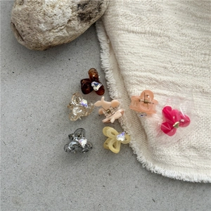 Detail view of six mini resin claw clips in assorted colors on a textured stone surface