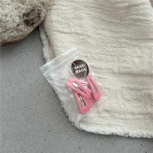 Close-up of pink matte metal hair clips in clear packaging with a handmade label