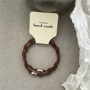 Close-up of brown wavy elastic hair ties with gold metal buckles and handmade card