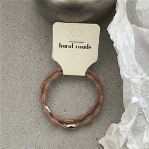 Detail view of two elastic hair ties with wavy texture and elegant gold metal beads