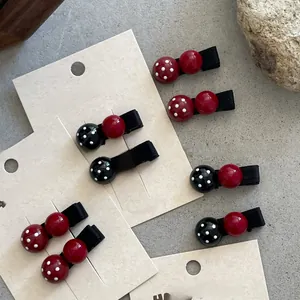 Close-up of red and black polka dot resin hair clips on handmade card display