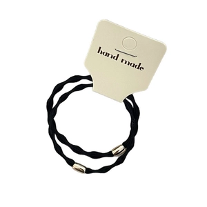 Elastic black hair ties with golden metal cylinders on a beige hanging card display