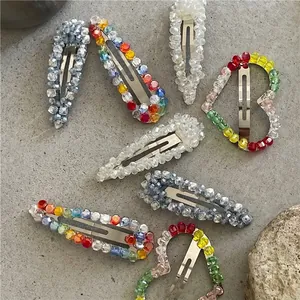 Luxurious crystal beaded teardrop and heart snap clips set on stone background
