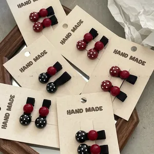 Detail of ladybug-style hair clips with red and black polka dot beads on a display card
