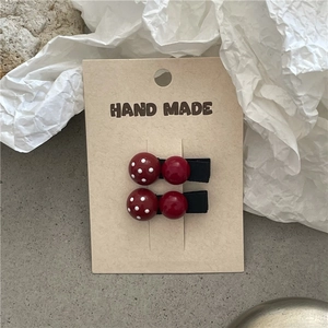 Detailed view of handmade polka dot hair clips on cardboard display background