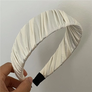 Détail de la texture satinée plissée sur ce serre-tête beige crème élégant