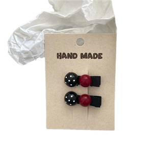 Handmade hair clips featuring black polka dots and dark red beads on a fabric base