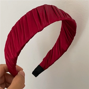 Gros plan d'un serre-tête en satin plissé bordeaux avec texture plissée et embouts noirs