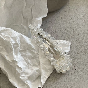 Detailed view of handmade crystal beaded hair clip on a textured stone surface