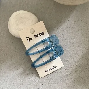 Detail of blue translucent water-drop hair clips on card packaging with metallic duckbill clip